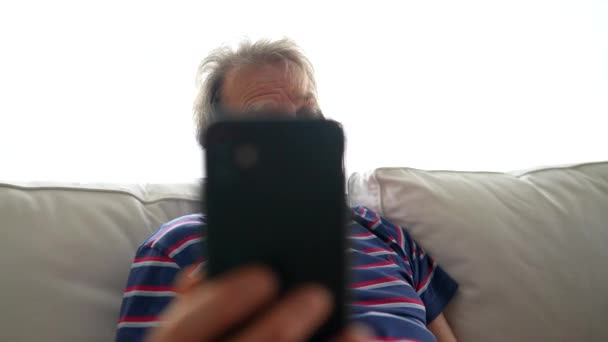 拿着手机的老年人用智能手机用视频讲话 在客厅沙发上使用现代技术设备的老实人 — 图库视频影像