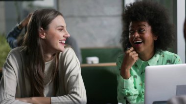 Kafede oturmuş gülen ve gülümseyen genç bir arkadaş grubu. Gerçek hayatta kadınlar kafe 'de güler ve gülümser.