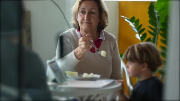 奶奶在午饭时间和孙子在阳台上聊天时喂孙子 糖果奶奶喂小男孩水果 — 图库视频影像