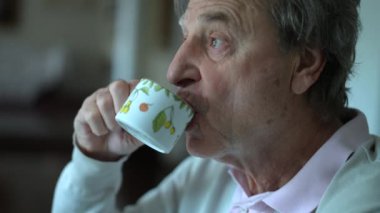 Sabah kahvaltısında kahve içen kıdemli bir adam. Yakın çekim yaşlı insan yüzü yudumlayan kafe
