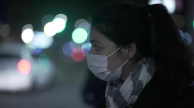 Gece yarısı Cavid-19 maskesi takan bir kadın caddeden karşıya geçmek için bekliyor.