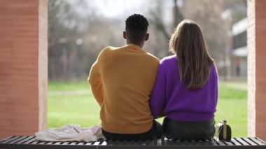 Dışarıda bankta oturan ırklar arası bir çiftin arkası.