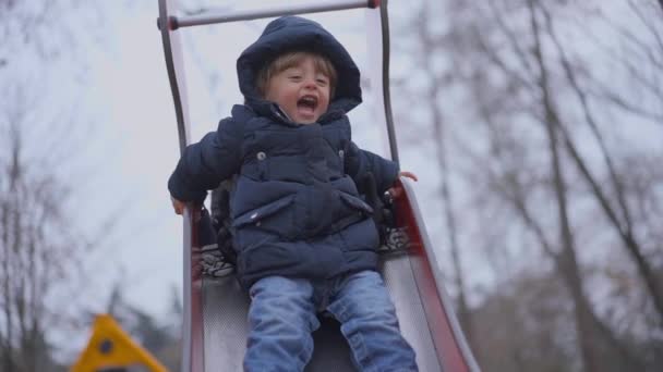 Χαρούμενο Αγοράκι Που Γλιστράει Στην Παιδική Χαρά Κατά Χειμερινή Περίοδο — Αρχείο Βίντεο