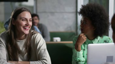 Kafede oturmuş gülen ve gülümseyen genç bir arkadaş grubu. Gerçek hayatta kadınlar kafe 'de güler ve gülümser.