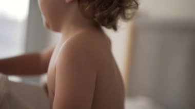 Yatağa uzanmış çarşaf çeken sevimli bir bebek. Bebek sabahları battaniyenin altında yatıyor.