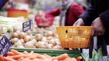 İnsanlar sokak pazarından alışveriş yapıyor. Sebzeler sergileniyor. Havuçlar yakın plan