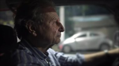 Şehirde gece araba süren kıdemli bir adam. Odaklanmış olgun yaşlı erkek sürücünün yakın çekimi. 