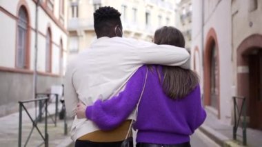 Sokakta yürürken kolları birbirine dolanmış ırklar arası bir çift.