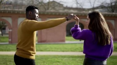 Zenci adam dışarıda kız arkadaşıyla dans ediyor, ırklar arası sevgi dolu çift parkta dans ediyor.