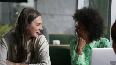 Kafede oturmuş gülen ve gülümseyen genç bir arkadaş grubu. Gerçek hayatta kadınlar kafe 'de güler ve gülümser.