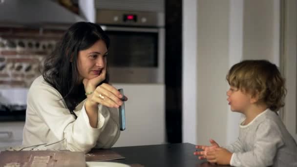 Mały Chłopiec Rozmawia Członkiem Rodziny Przez Wideokonferencję Smartfonie Kuchni Matką — Wideo stockowe