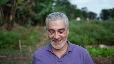 Happy older man walking forward in farm. Senior person portrait face at farmland