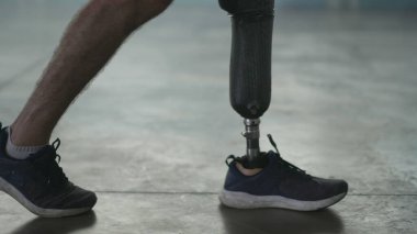 Kapalı alanda protez bacağıyla yürüyen engelli biri. Ampüte adam protez bacakla yürür.