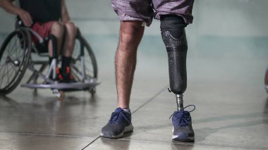 Protez bacaklı engelli biri. Arka planda tekerlekli sandalyedeki biri var. Azim ve motivasyon kavramı