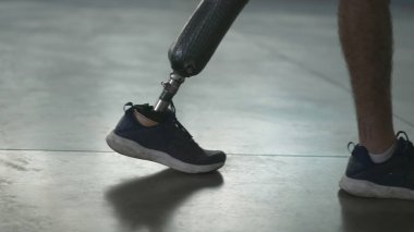Kapalı alanda protez bacağıyla yürüyen engelli biri. Ampüte adam protez bacakla yürür.