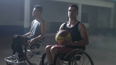 Tekerlekli sandalyedeki iki özürlü İspanyol basketbolcu. Kameraya bakan genç bir Güney Amerikalı 'nın portresi