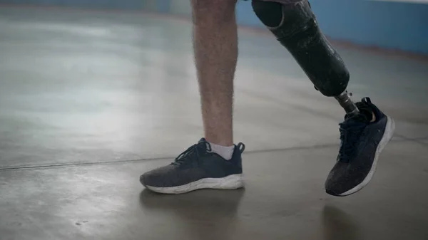 Disabled person walking with his prosthetic leg indoors. Amputee man walks with prosthetis legDisabled person walking with his prosthetic leg indoors. Amputee man walks with prosthetic leg