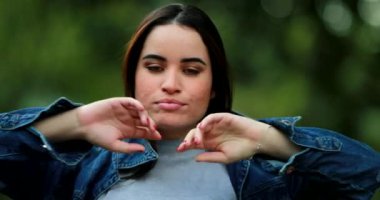 Genç bir kadın kot ceket giyiyor ve saçlarını düzeltiyor.