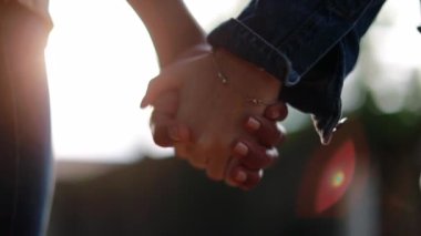 Close-up of hands joining together with sunlight flare in the background