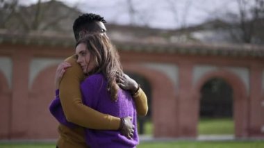 Irklar arası genç çift dışarıda sarılıyor. Parkta dikilen empatik kucaklaşma