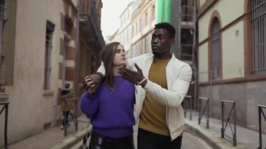 Sokakta birlikte yürüyen ırklar arası genç bir çift. Afrikalı erkek arkadaşın kız arkadaşına sarılması