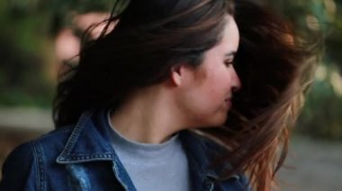 Güzel kız parkta saçlarıyla oynuyor gülümsüyor, mutlu ve özgür hissediyor.