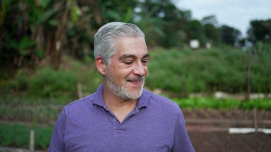 Happy older man walking forward in farm. Senior person portrait face at farmland