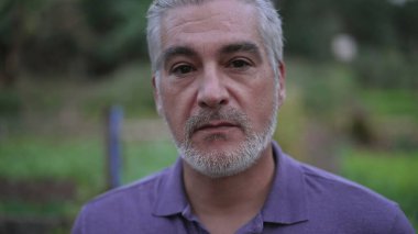 Portrait of a senior man with serious expression. Closeup face of older person standing outdoors in the evening