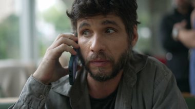 30 'lu yaşlarda bir adam telefonda konuşuyor. Elinde akıllı telefon cihazıyla gülümseyen biri konuşuyor. İletişim için modern teknoloji aygıtı