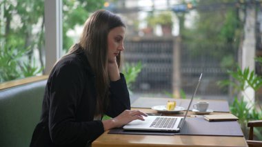 Kahve dükkanında dizüstü bilgisayar kullanan samimi bir genç kadın. Kafe restoranında bilgisayarın önünde uzaktan kumandayla çalışan biri. Klavyede yazan kız e- posta yazıyor
