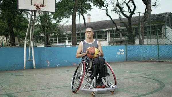 Tekerlekli sandalyedeki engelli atlet kameraya bakarak basketbol oynuyor. Azim ve motivasyon kavramı