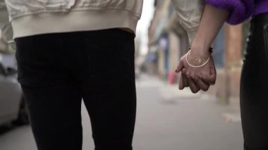 Genç siyah adam ve beyaz kadın şehirde el ele tutuşuyorlar. Irklar arası sevgililer