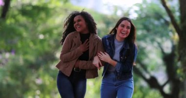 İki mutlu kız arkadaş sohbet ederken birlikte gülüyorlar.