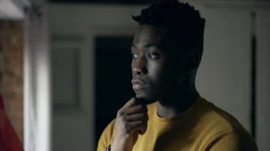 Siyah Afrikalı adam pencerenin kenarında durup düşünüyor.