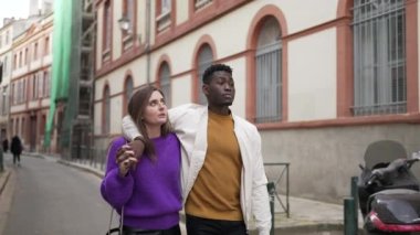 Sokakta birlikte yürüyen ırklar arası genç bir çift. Afrikalı erkek arkadaşın kız arkadaşına sarılması