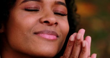 Düşünceli siyah Afrikalı kız gözleri kapalı, meditasyon yaparken gülümsüyor.