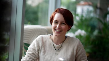 Mutlu kızıl saçlı bir kadın, gülüyor ve gülümsüyor. Kafede oturan portre kızı.