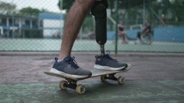 Protez bacağı olan engelli biri kaykay kullanıyor. Atletik kaykaycı ampüte