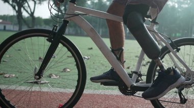 Dışarıda bisiklet süren protez bacaklı biri. Engelli bir sporcu bisiklet sürüyor