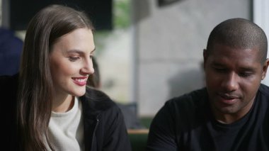 Kafede oturan çeşitli erkek ve kadınlar. Kafede siyah bir adamla beyaz bir kız.