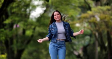 Eğlenceli, mutlu, genç bir kadın doğada neşeyle dans ediyor.