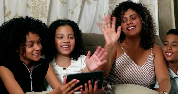 Brazilian family talking on video with tablet communication waving hello