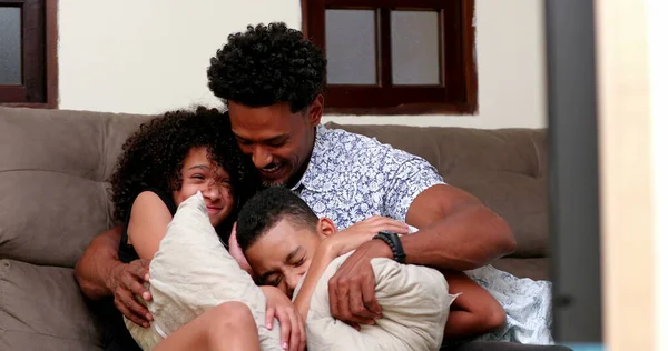 Candid black parent embracing kids at home