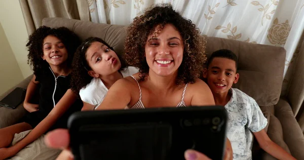 ブラジル人の母親と子供たちはスマートフォンでソファで写真を撮る — ストック写真