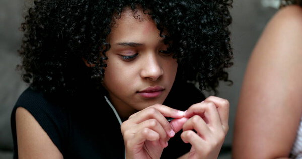 Girl looking at nails, candid person nail biting