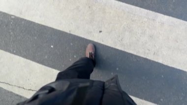 Yaya geçidi zebra çizgilerinde yürüyen birinin görüntüsü. İnsan botlarının bakış açısı yavaş çekimde adım adım