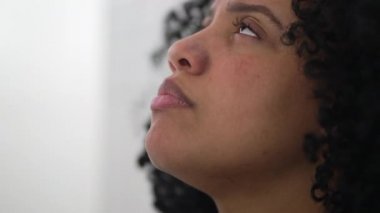 Genç kadın umutla ve inançla gökyüzüne bakıyor. Dua eden ruhani Afrikalı Amerikalı. Düşüncelere dalmış dindar kişi