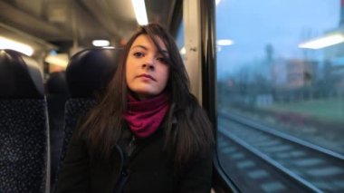Trenle seyahat eden genç bir kadın yanından geçen manzaraya bakıyor. Hareket halindeki trende oturan kız 120 fps yavaş çekimde dışarı bakıyor.