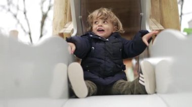 Küçük çocuk oyun parkında kayıyor.