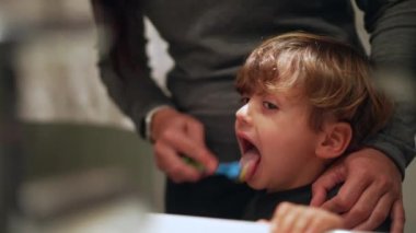 Ebeveyn, diş fırçasıyla çocuk dili fırçalıyor. Anne çocuk ağzını temizliyor. Diş sağlığı konsepti 